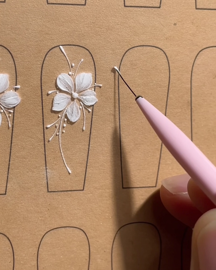 A close-up of a nail tip showing five precise white gel dots arranged in a small circle, acting as a guide for a five-petal flower.