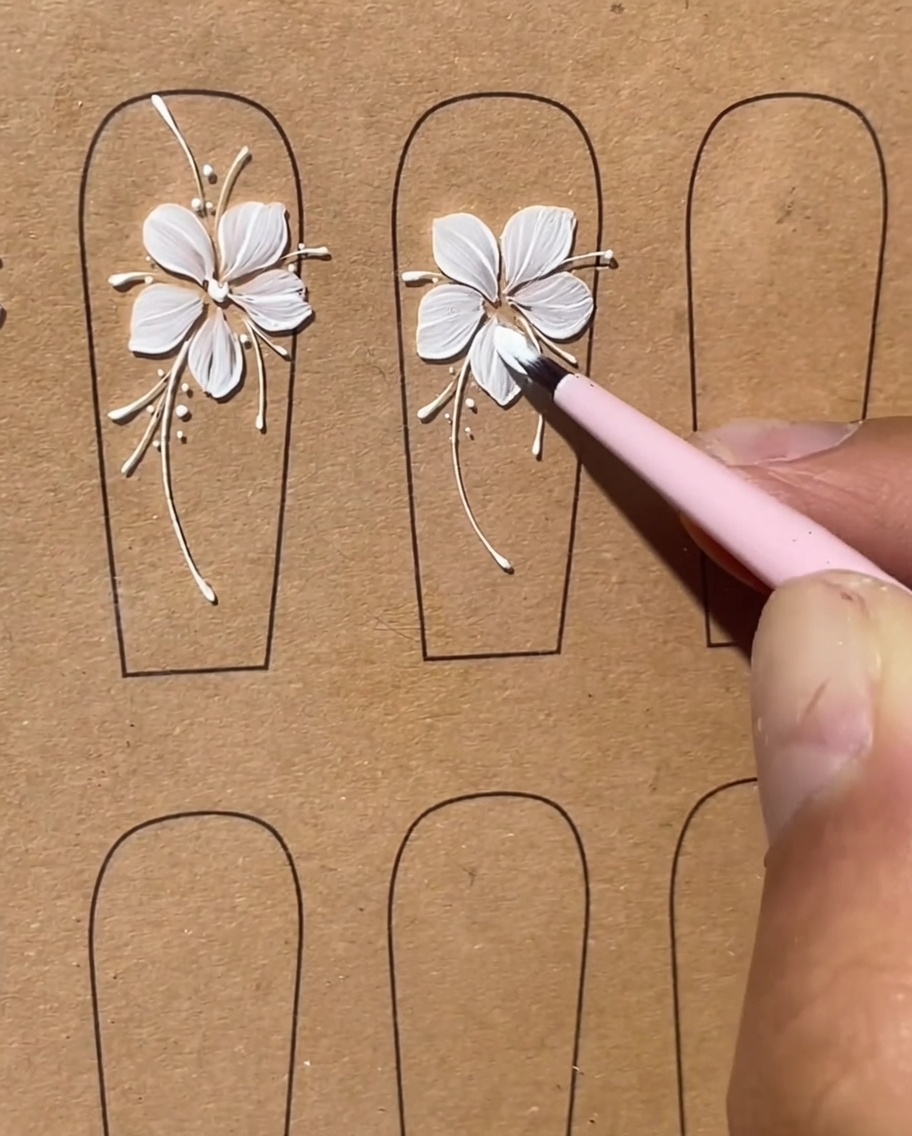 A flat brush creating a second white gel petal next to the first on the nail surface.