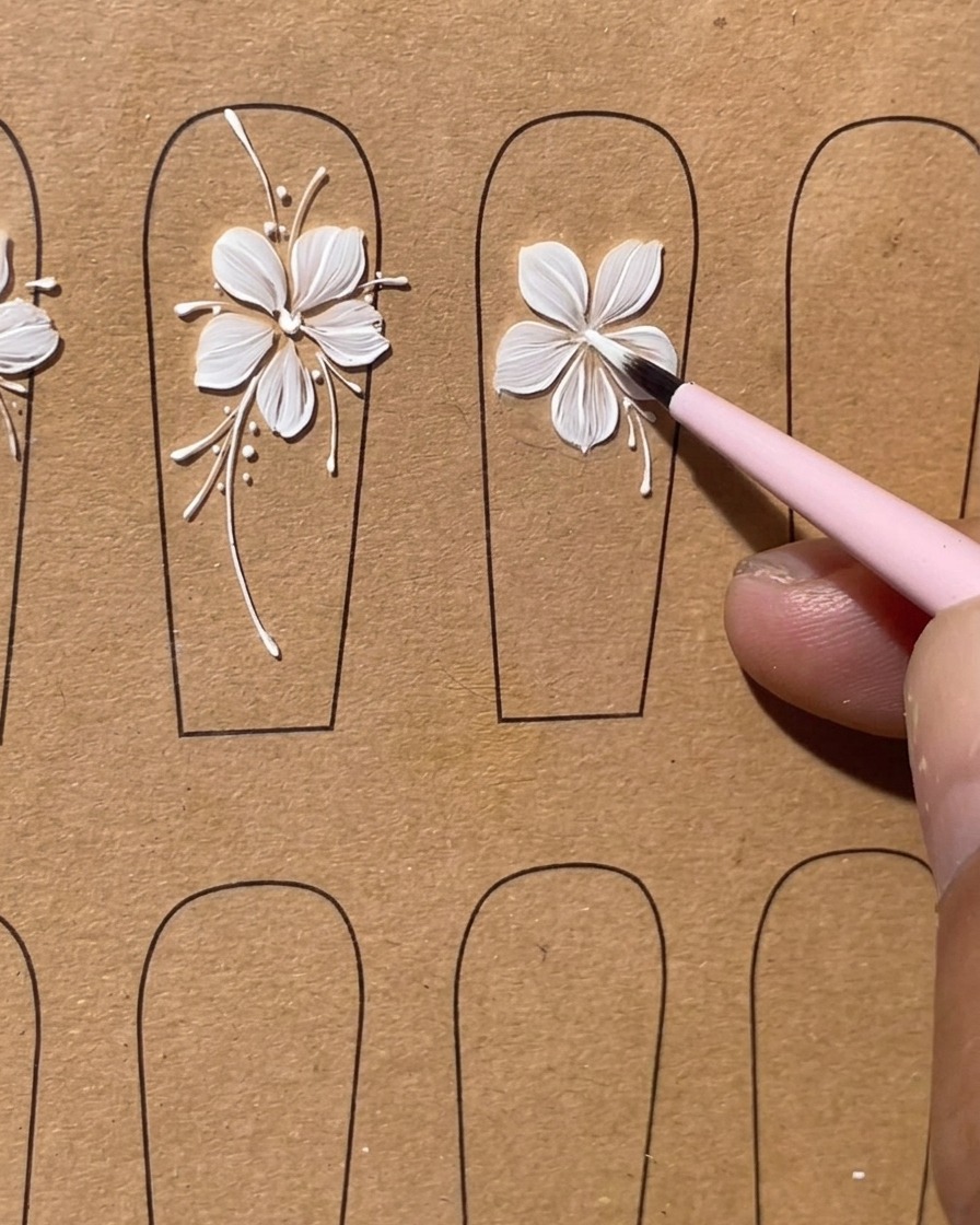 A flat brush forming the fourth white gel petal on the nail tip.