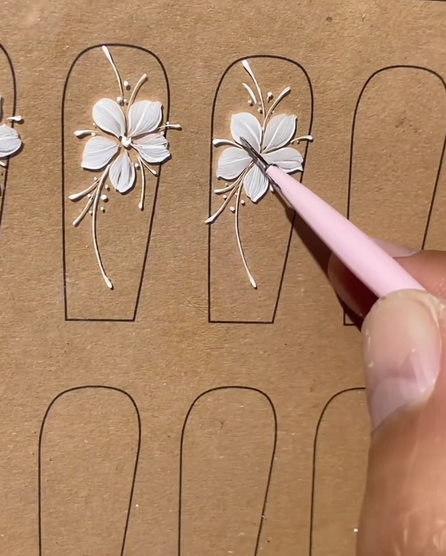A final close-up of a completed white floral nail design with all lines appearing clean and refined.