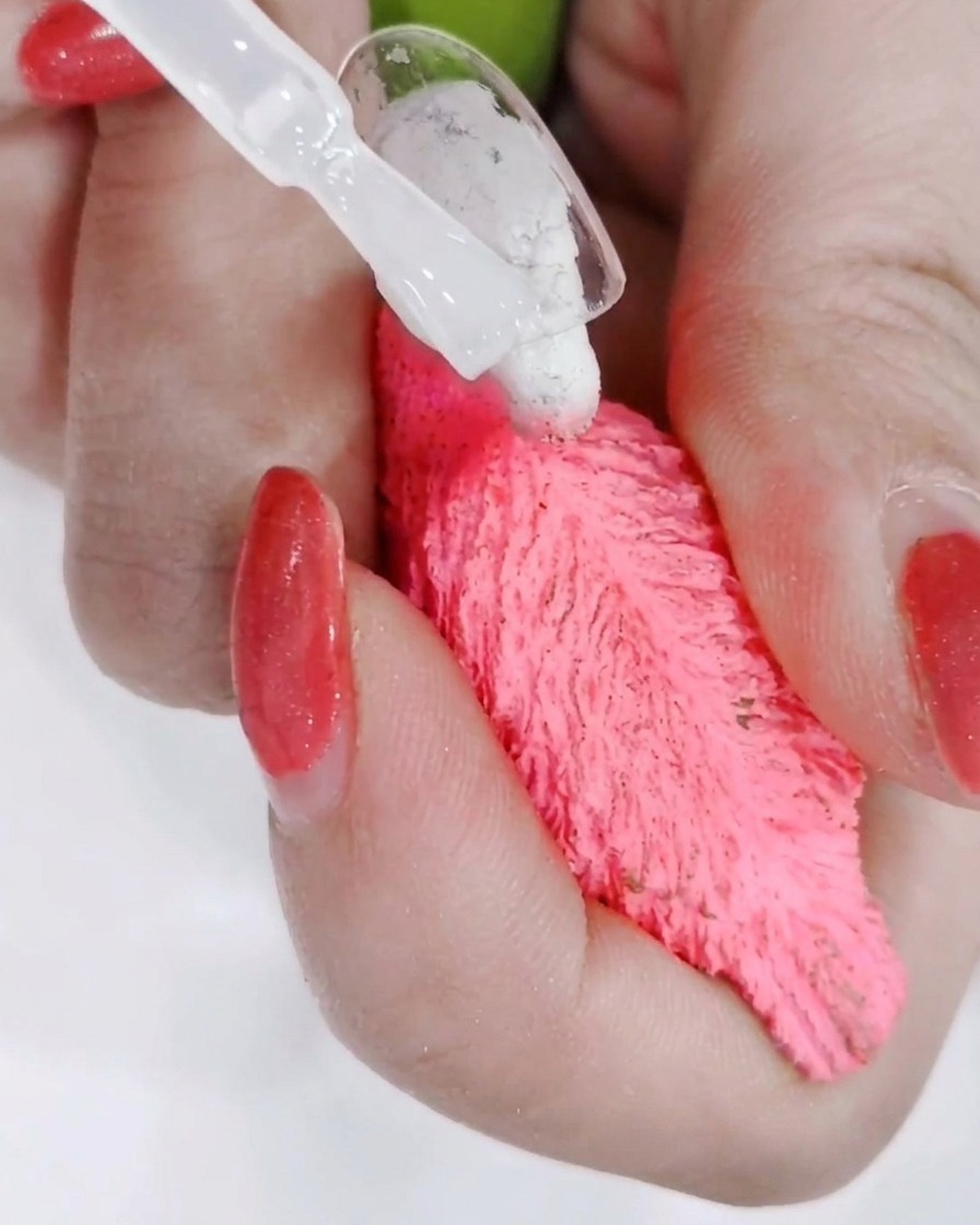 A hand positioned under a professional UV nail lamp with the light curing the freshly applied top coat.