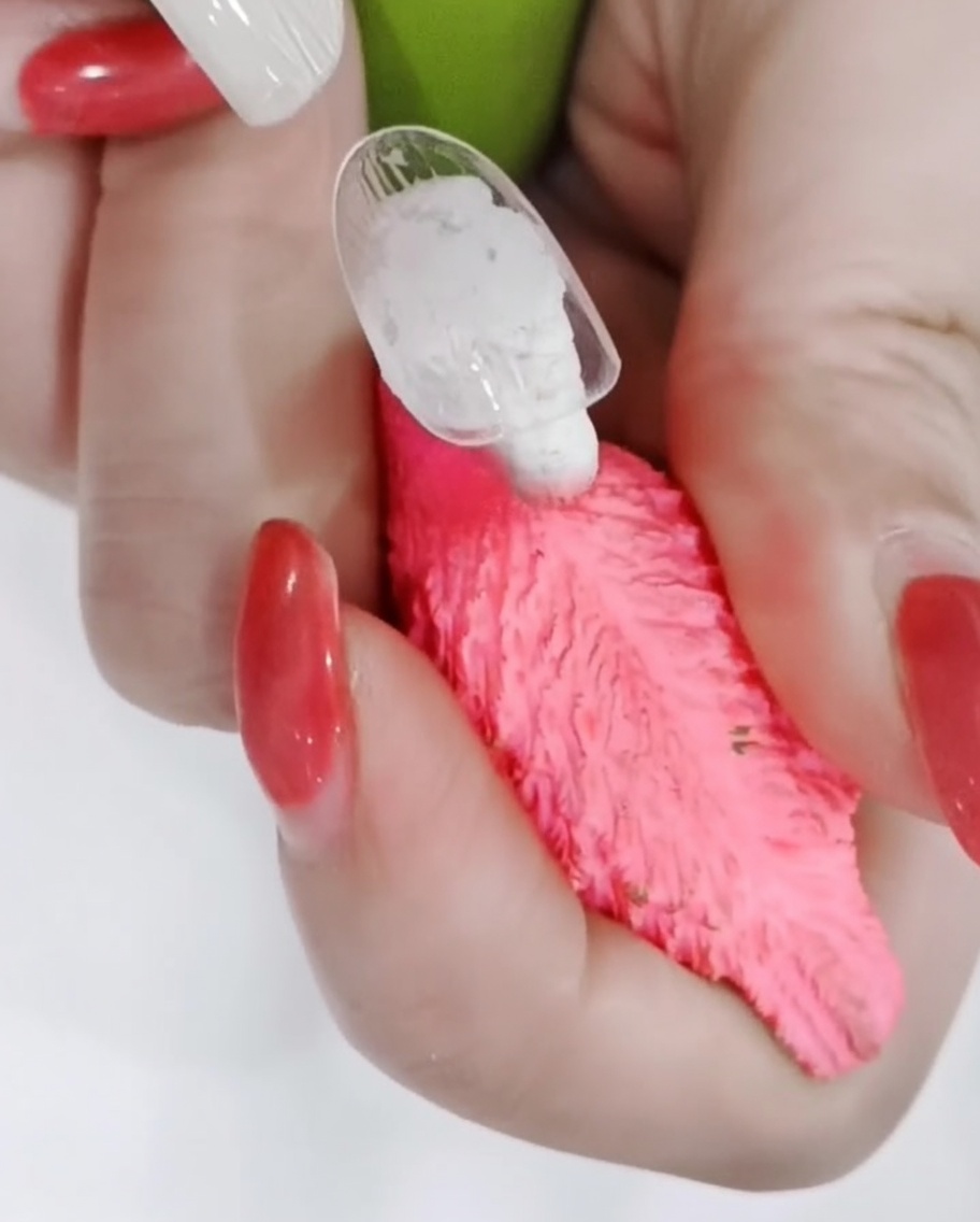 A close-up shot showing a fine brush carefully outlining the edges of white daisy petals on a matte nail.