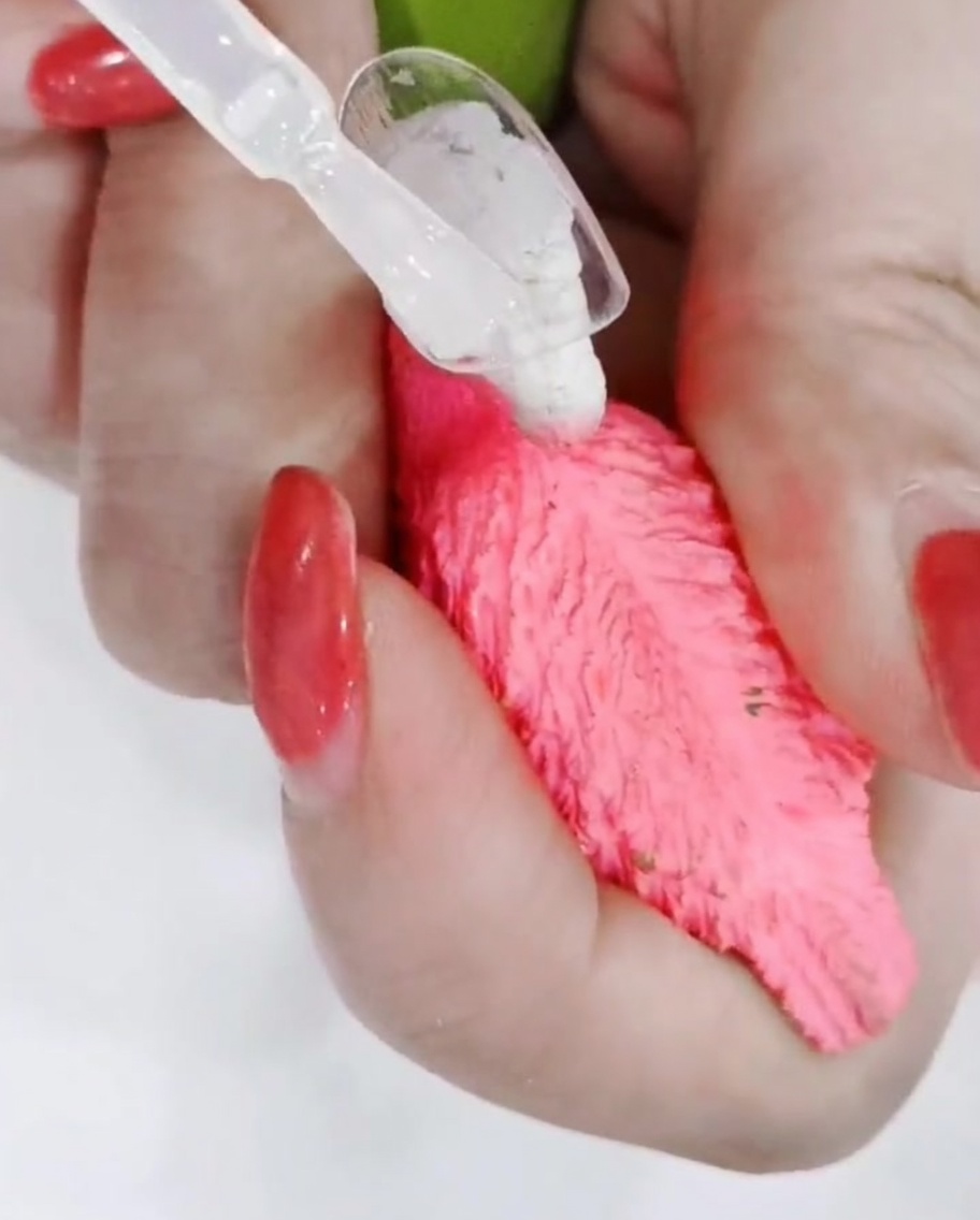 A close-up of a nail brush precisely outlining the edges of a hand-painted daisy on a matte nail surface.