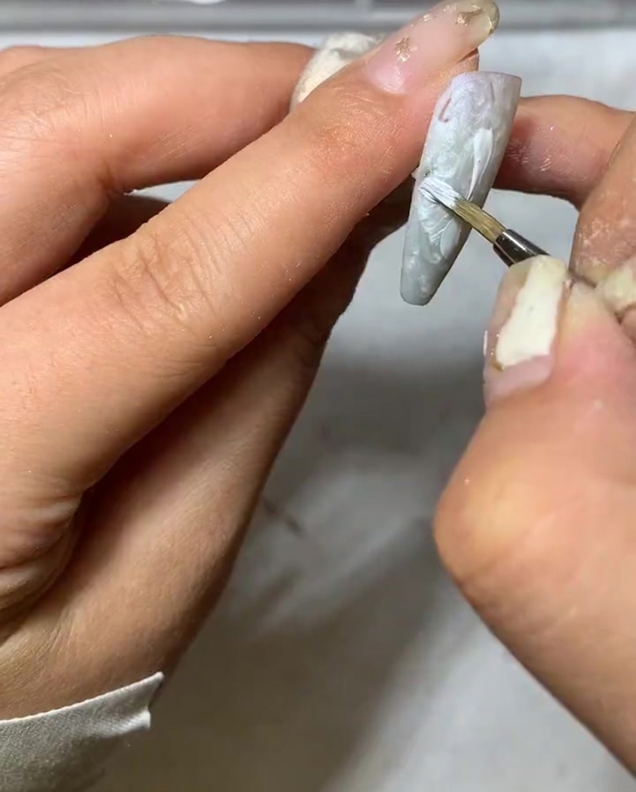 A detail shot showing the tip of a liner brush tapering the end of a white daisy petal.