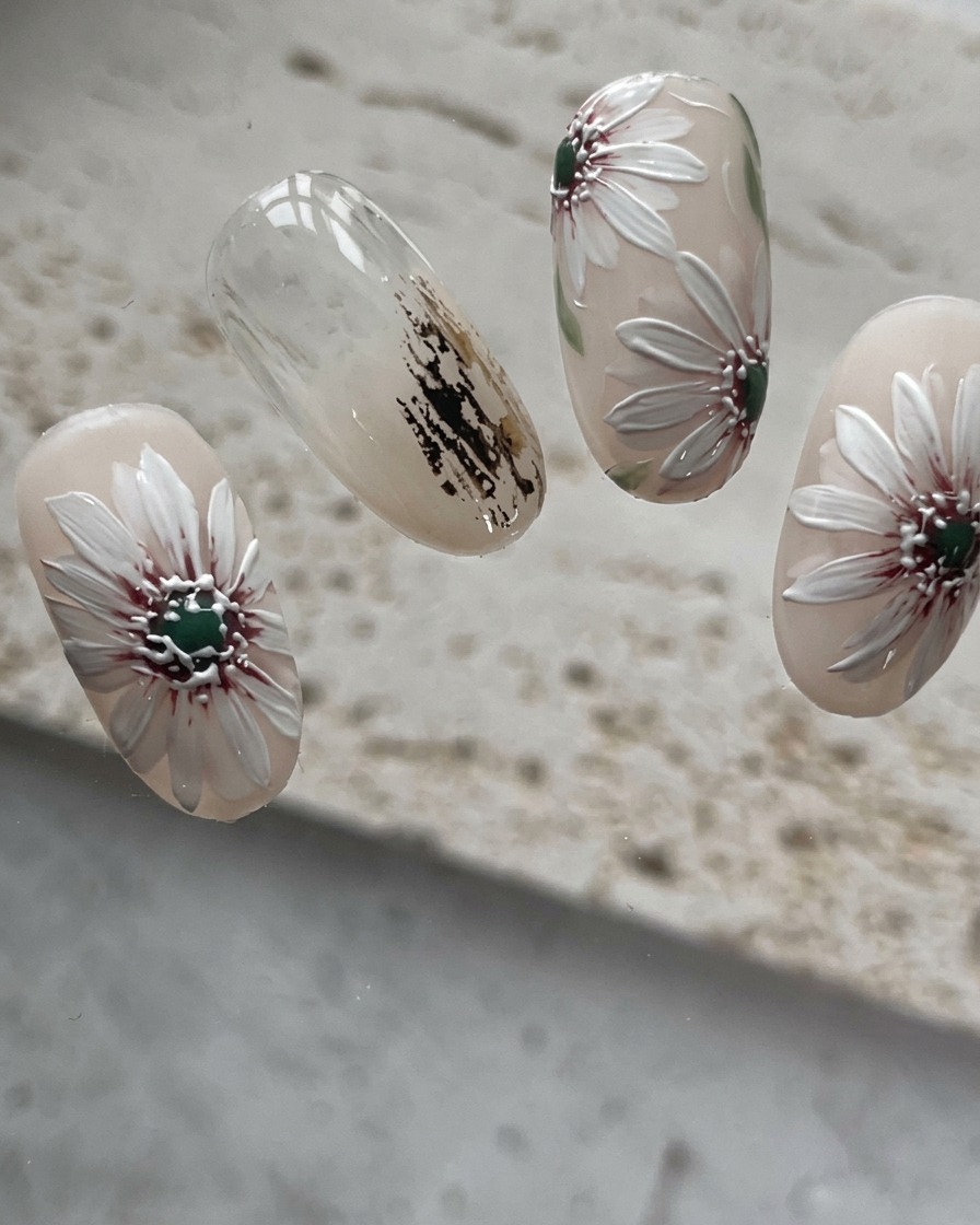 A close-up view of the nail with filler petals being painted into the gaps of the daisy.
