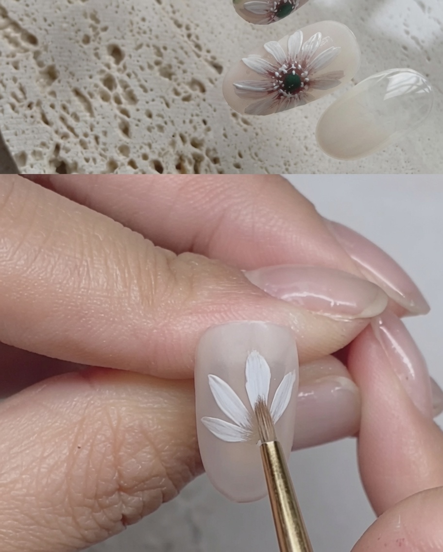 A close-up of a nail showing white gel brush strokes creating a second layer of daisy petals over the first.