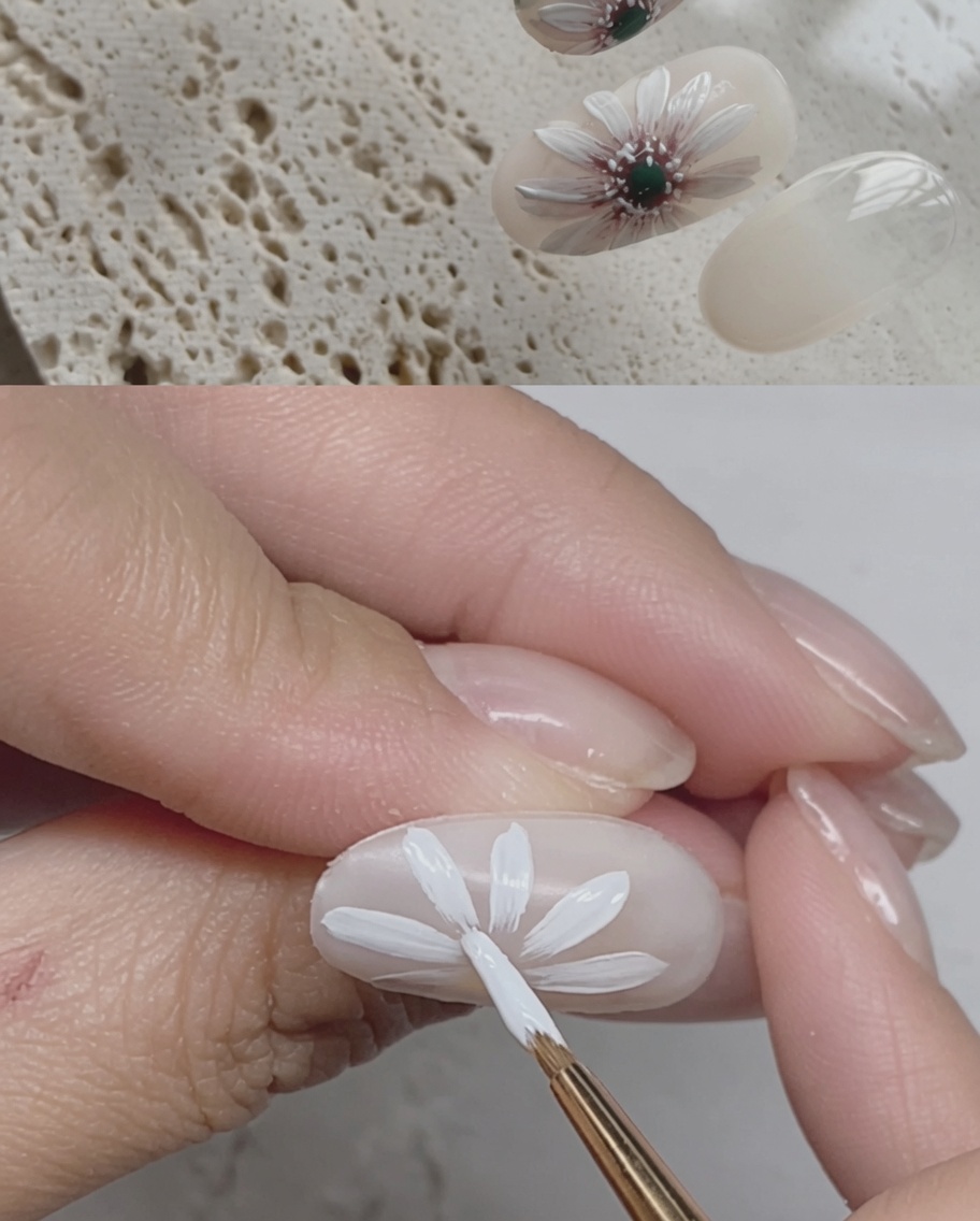 A brush applying a final glossy top coat over a completed daisy nail design.