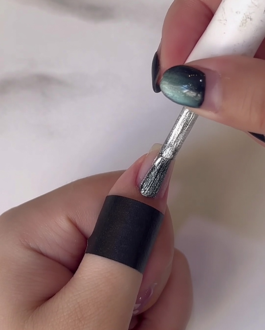 A dotting tool applying white gel dots to form flower petals on the nail.