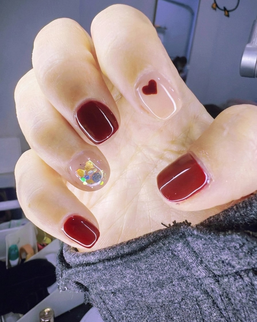 A brush applying a clear gel layer to the accent nail, keeping it wet for glitter application.
