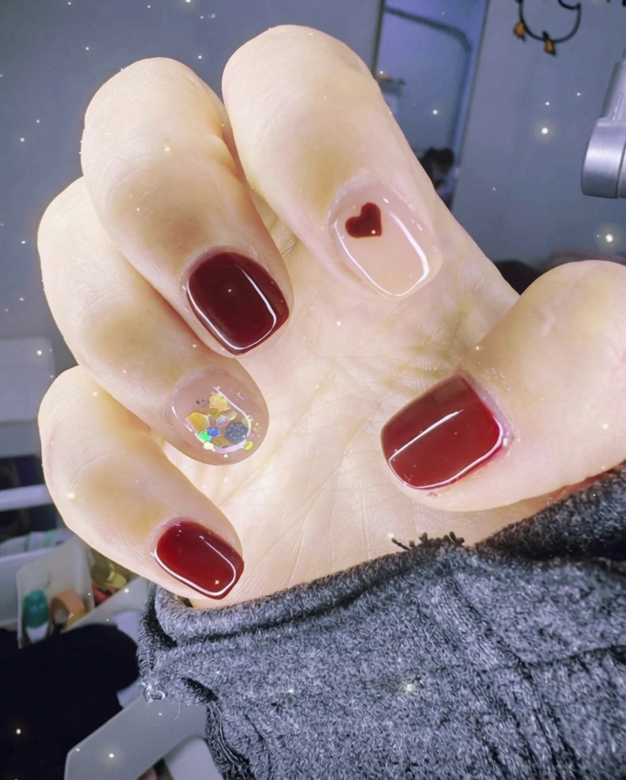 Close-up of tweezers placing gold foil pieces onto an accent nail coated in wet clear gel.