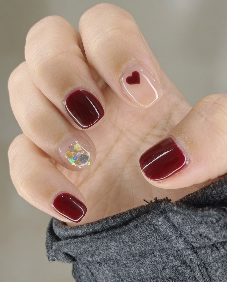 A brush applying clear glossy top coat over a manicured nail.