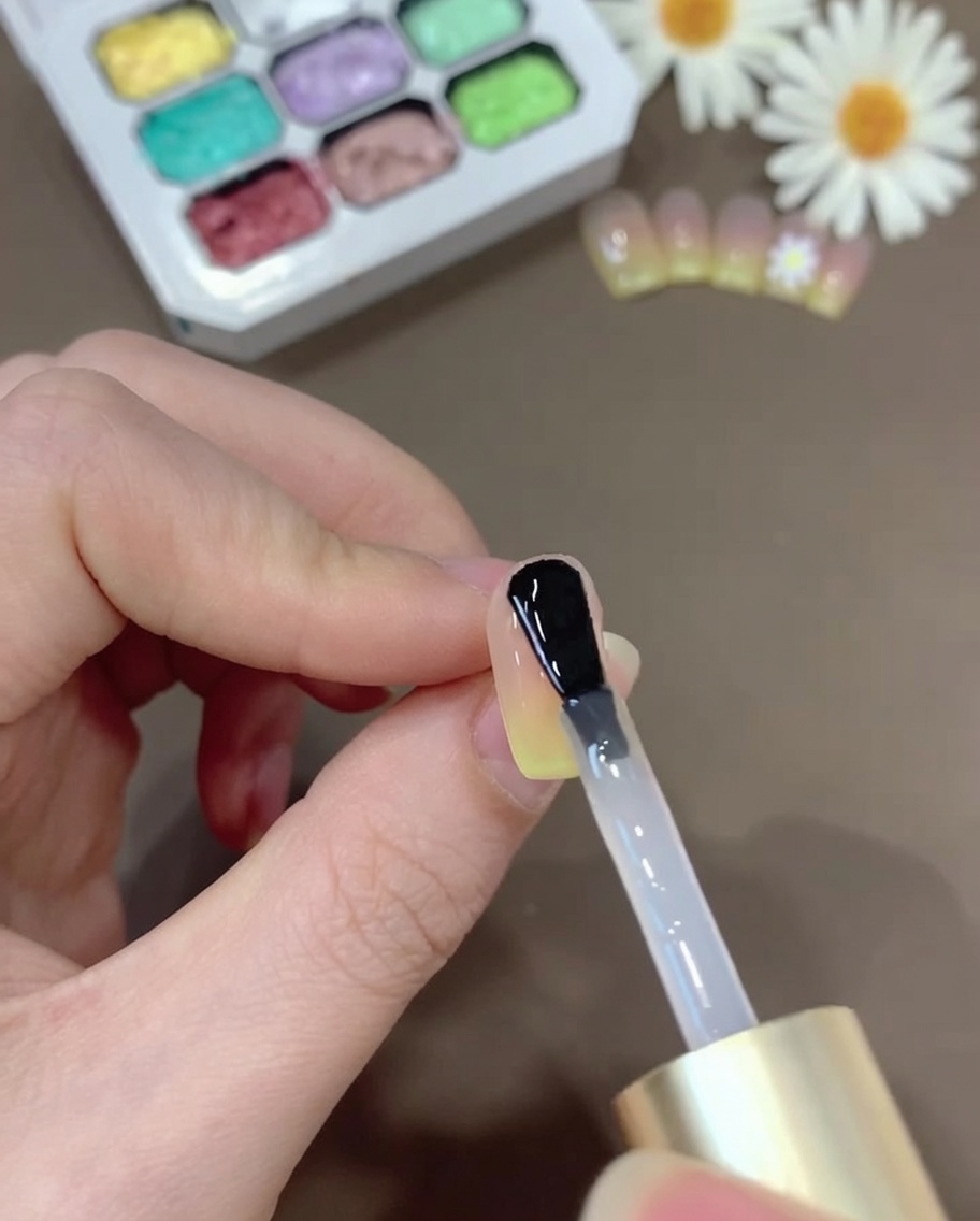 A brush applying a coat of clear top gel over the gradient nail to provide a glossy finish.