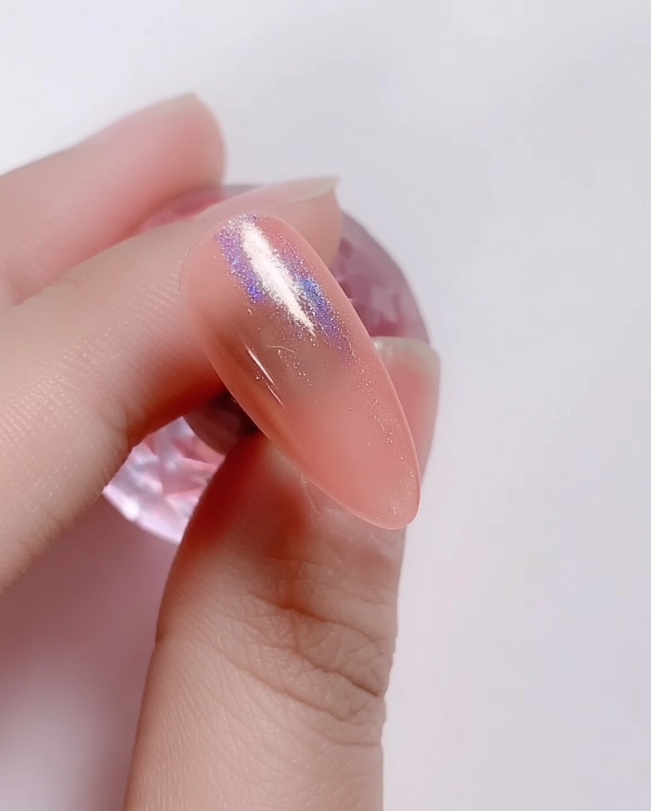 A small sponge applicator rubbing iridescent laser powder onto the pink gel nail.