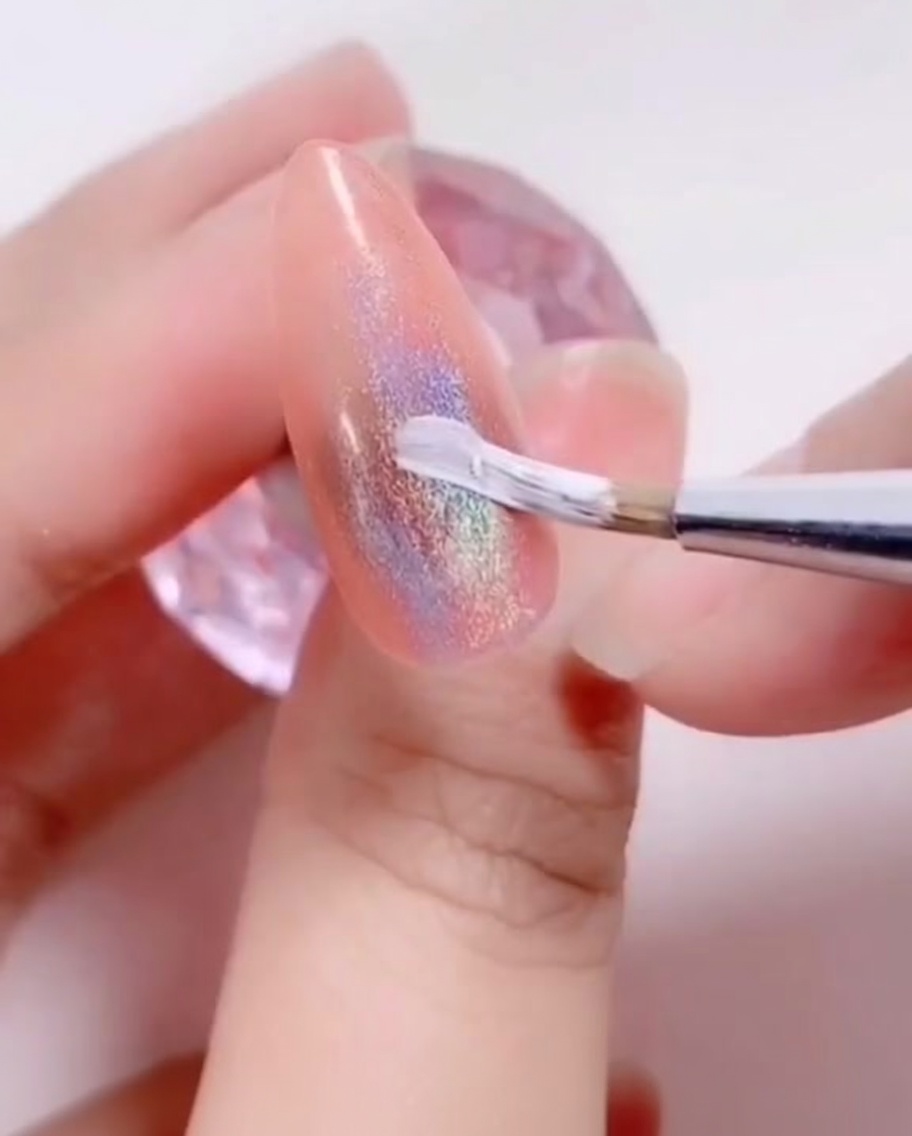 A fine liner brush applying a white gel petal design onto the nail surface.