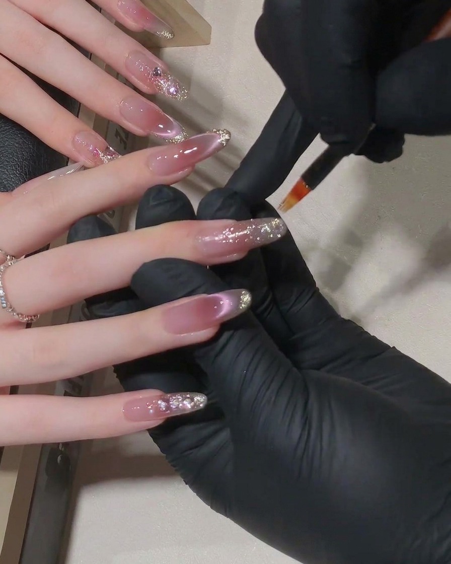 A set of nails inside an LED lamp curing under soft purple light.