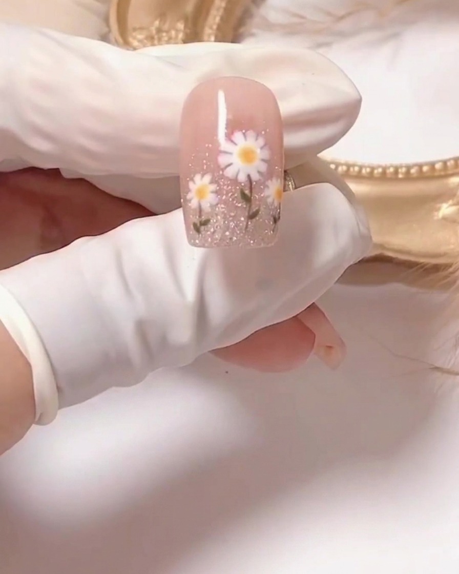 A close-up of a brush applying a sheer pink gel polish onto a prepped fingernail.