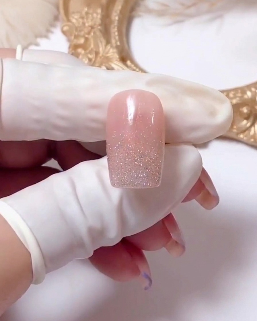A close-up view of a nail showing white gel lines being drawn in an X shape to start a daisy design.