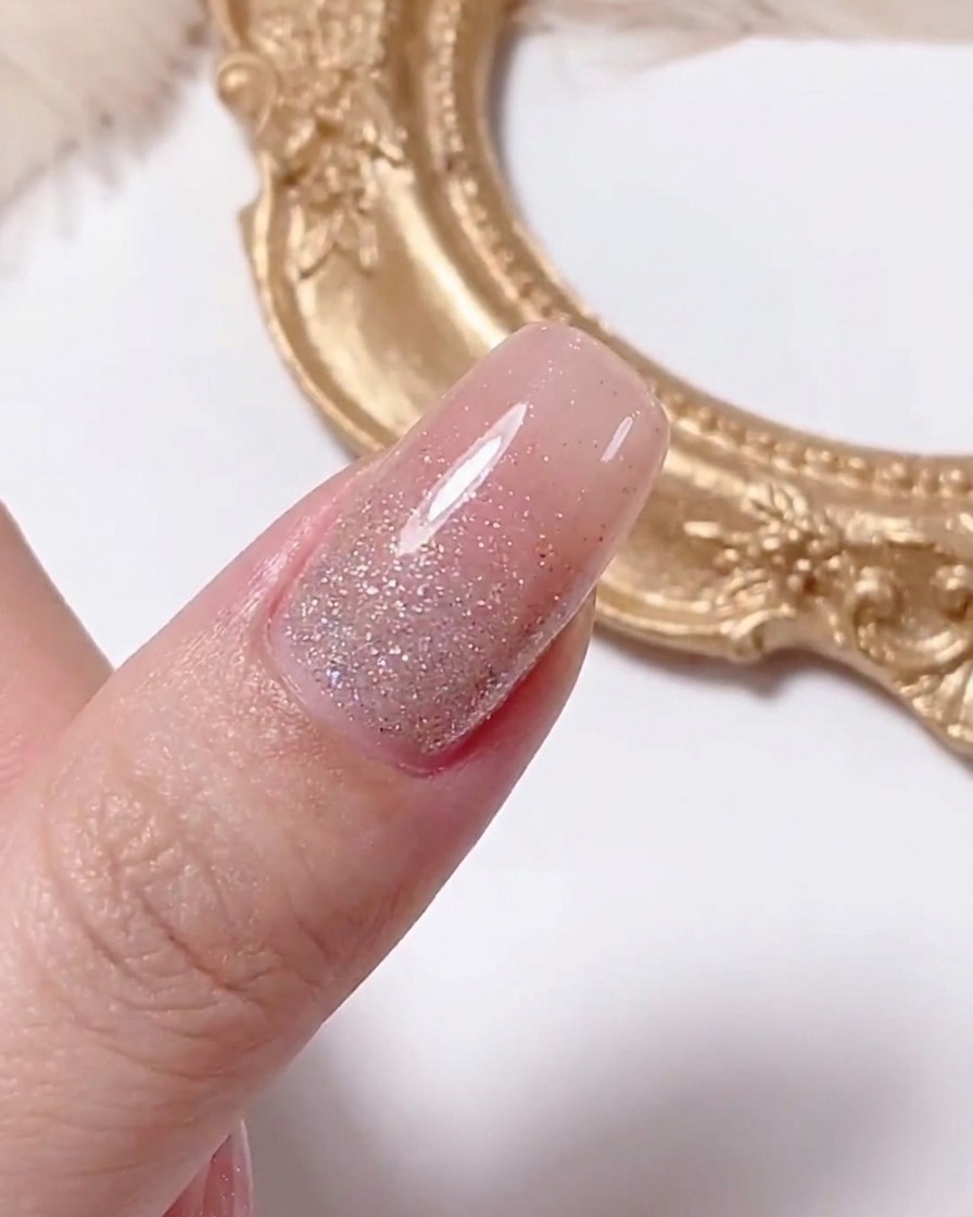 A dotting tool applying a small yellow dot to the center of a white daisy design on a nail.