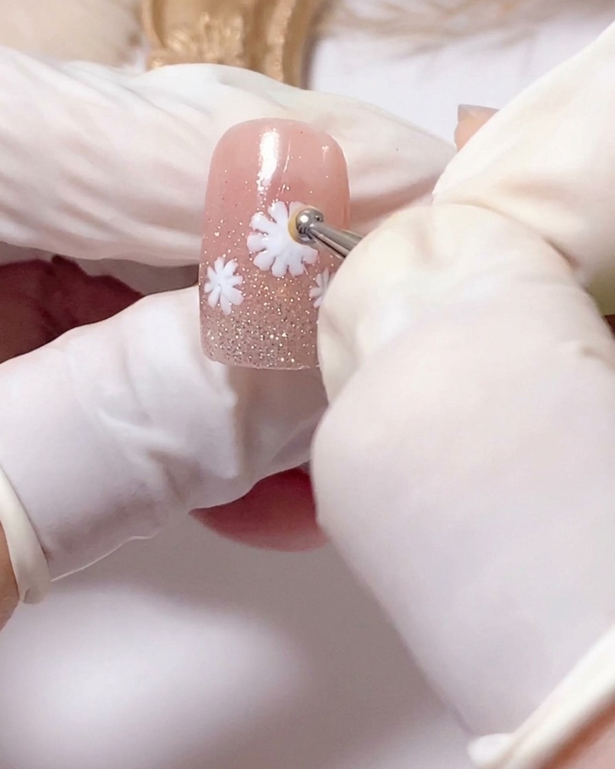 A tiny brush adding brown pigment to the yellow center of a daisy.