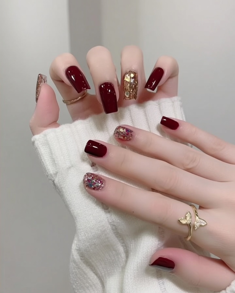A hand with finished, glossy red and glitter nails resting inside a UV/LED nail lamp for the final cure.
