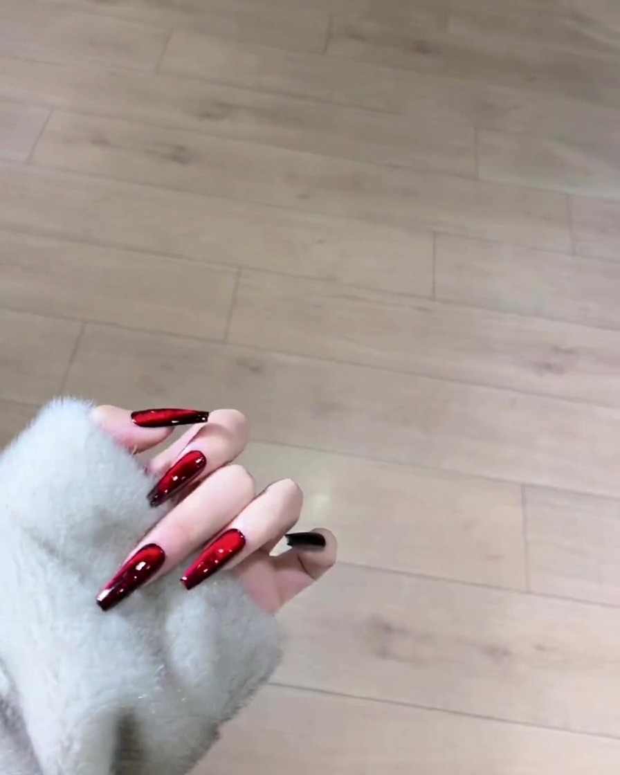 A brush applying a smooth coat of black gel polish over the entire surface of a natural-length nail.