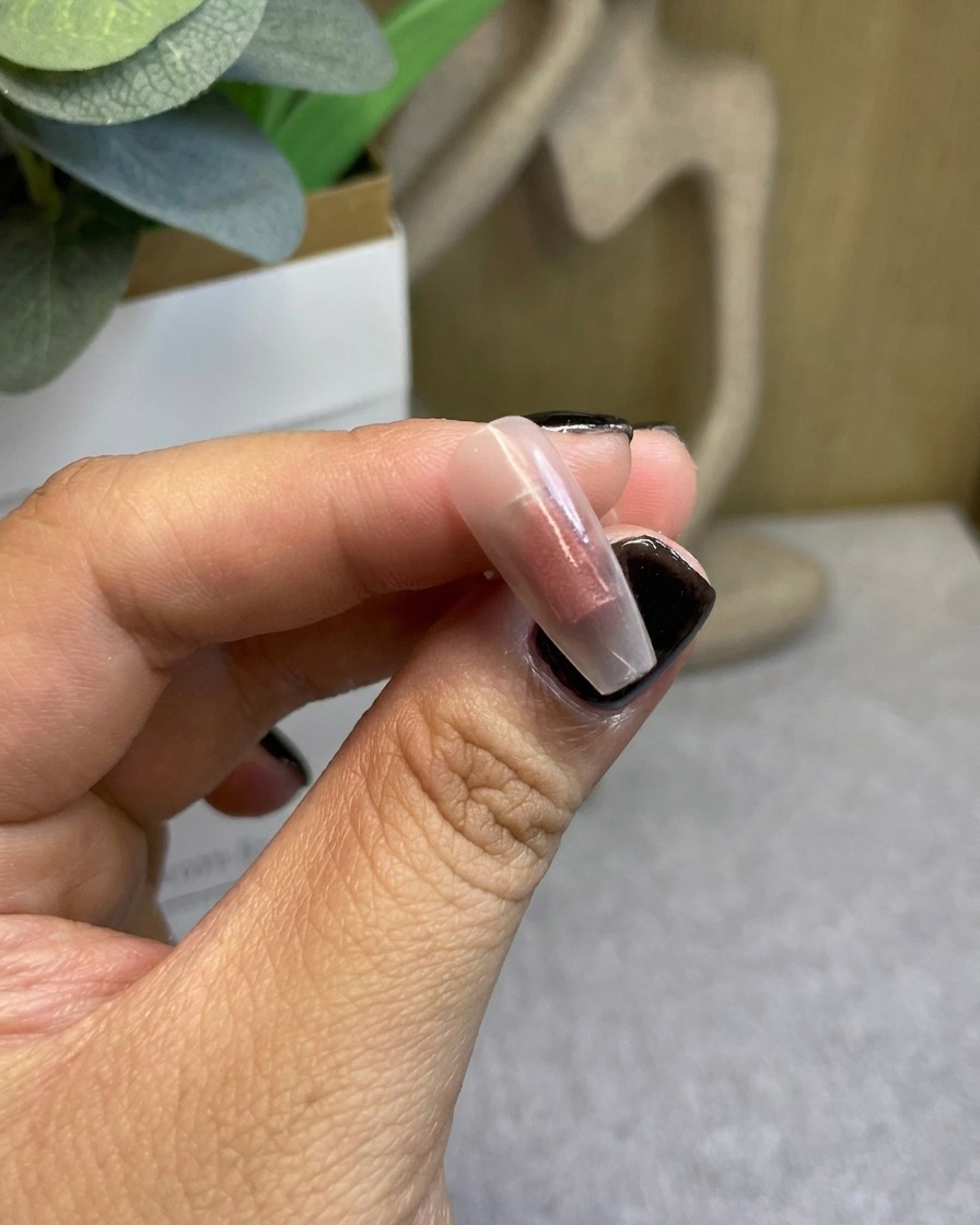 A nail tip with a concentrated red gradient color after initial curing.