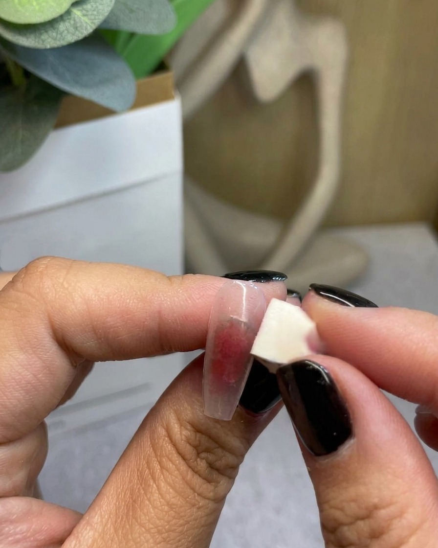 A close-up of a sponge blending red gel outwards to complete the gradient transition.