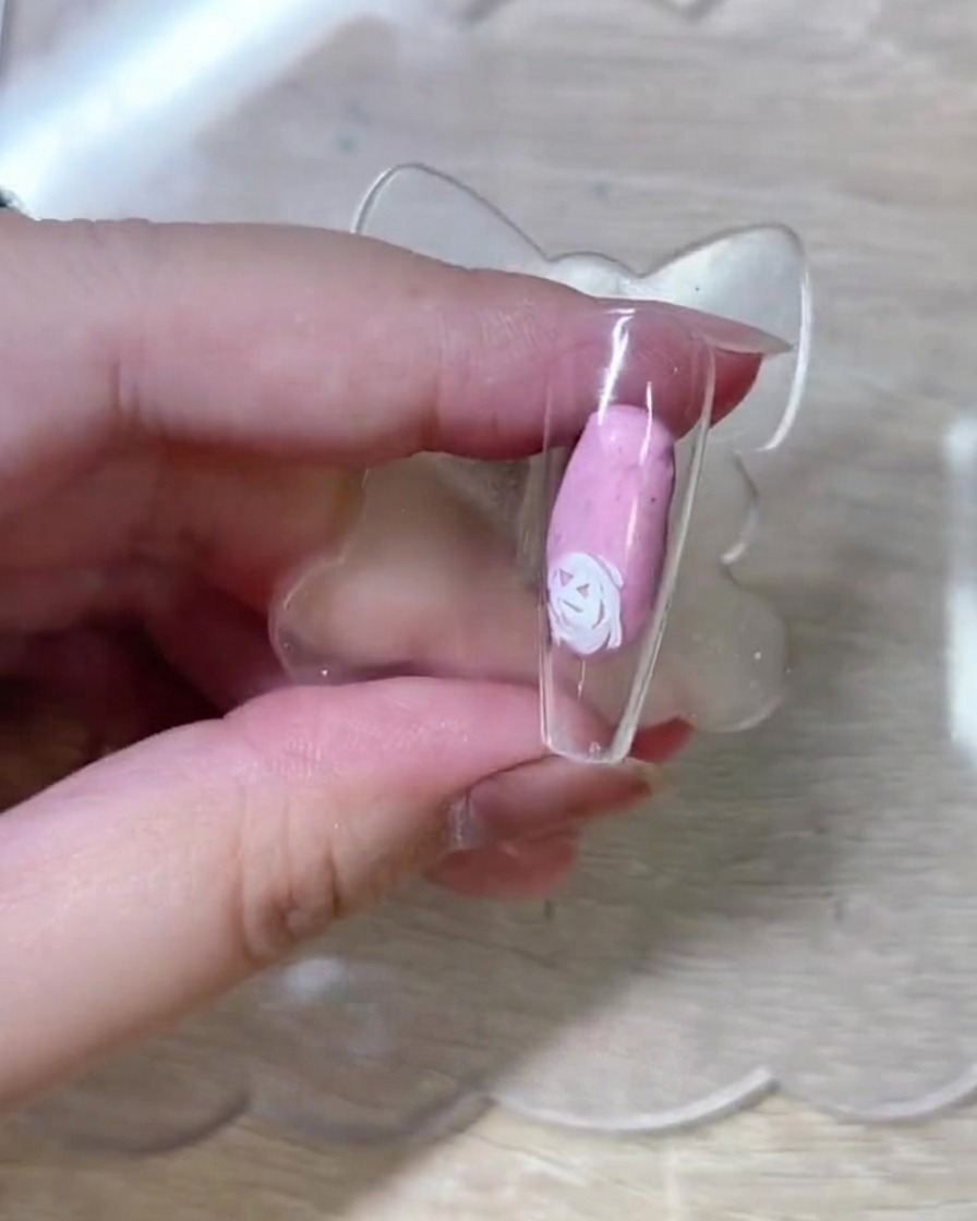 A close-up view showing additional white rose outlines being drawn onto the nail tip, building the floral composition.