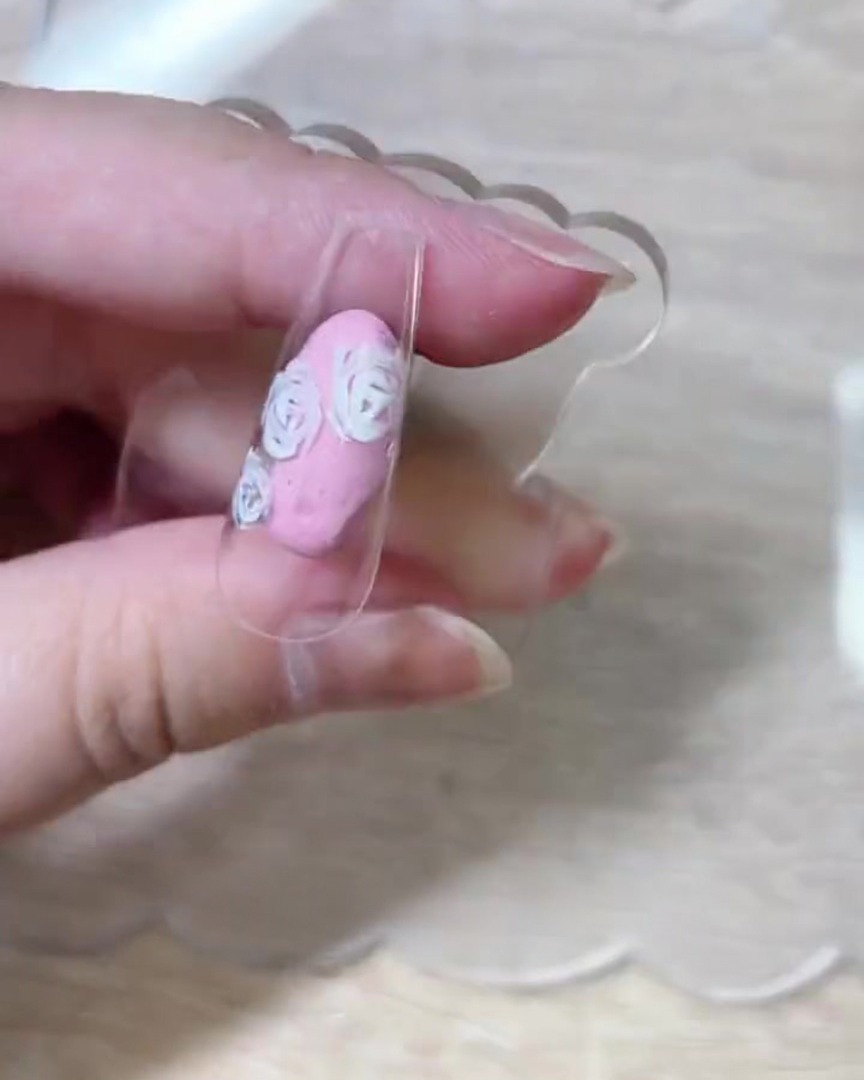 A top-down view of the nail tip showing the completed white rose petal outlines spread across the surface.