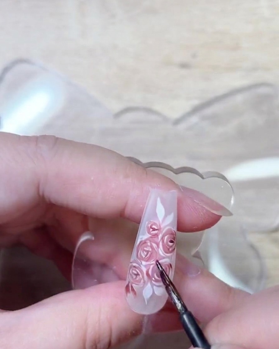 A brush detail shot showing deep red gel being applied to enhance the shadows and structure of the rose petals.