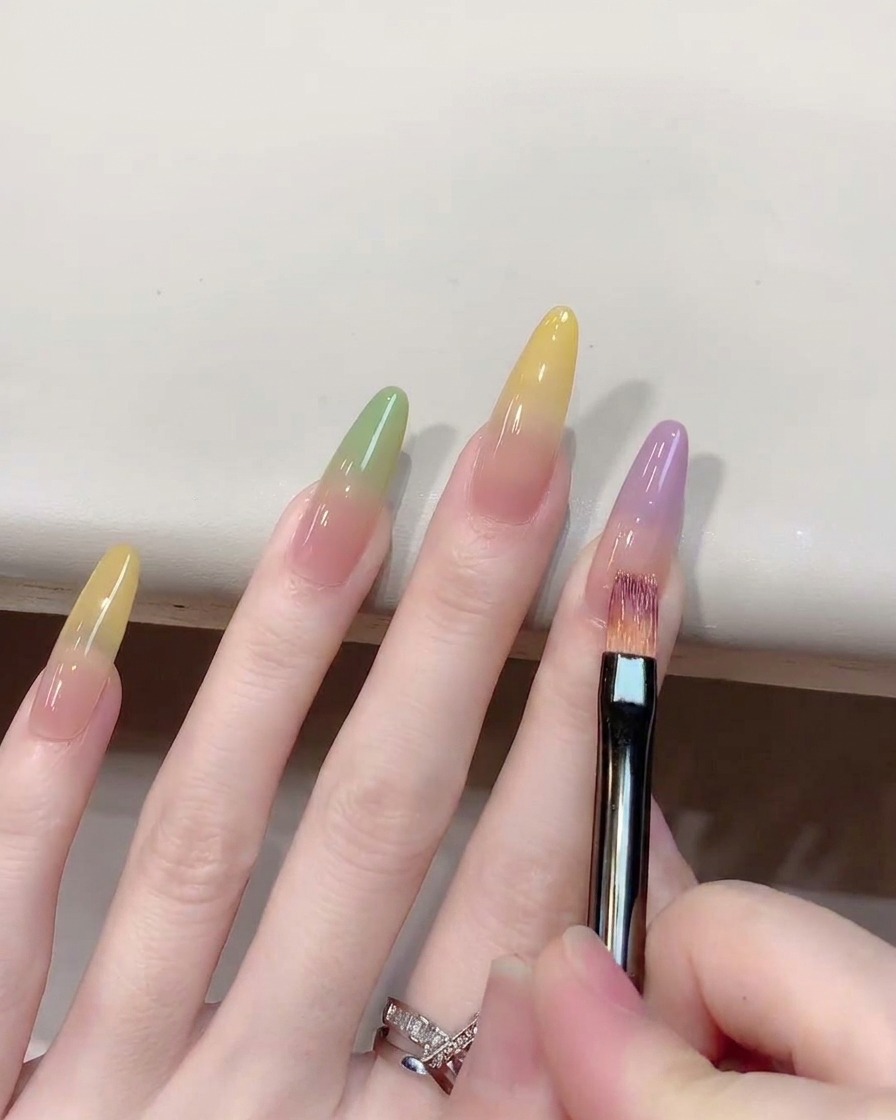 A close-up showing an ombre brush blending purple gel upwards on a nail.