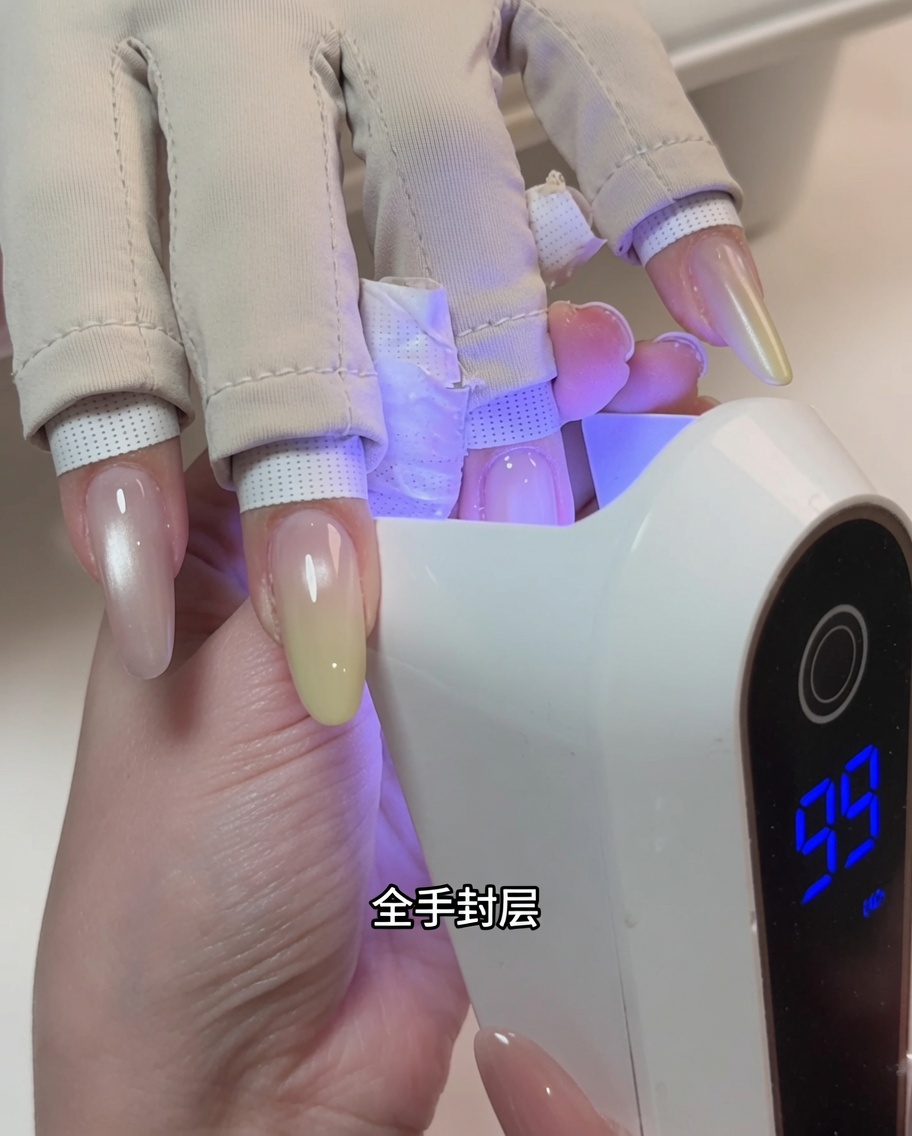 A hand positioned inside a professional UV nail lamp during the curing process.