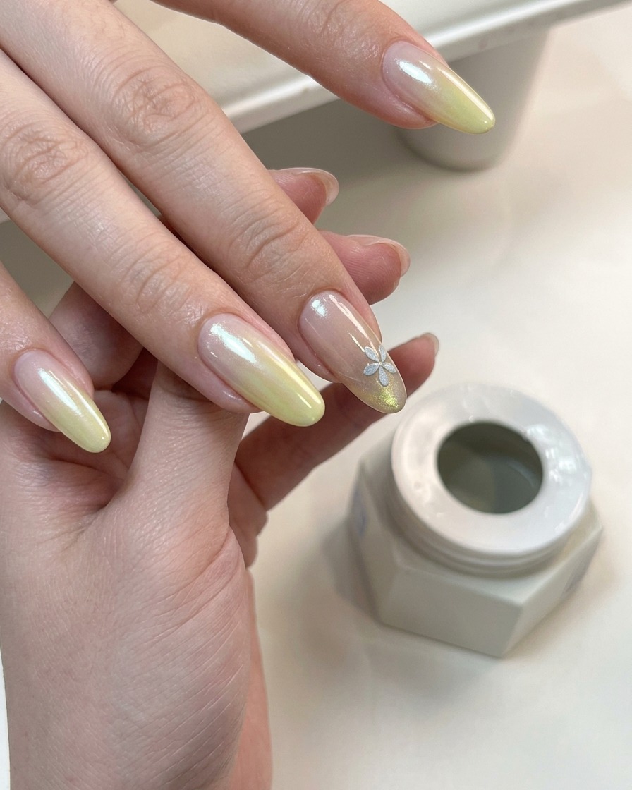 A hand with finished gradient and floral nail art curing under a UV lamp.
