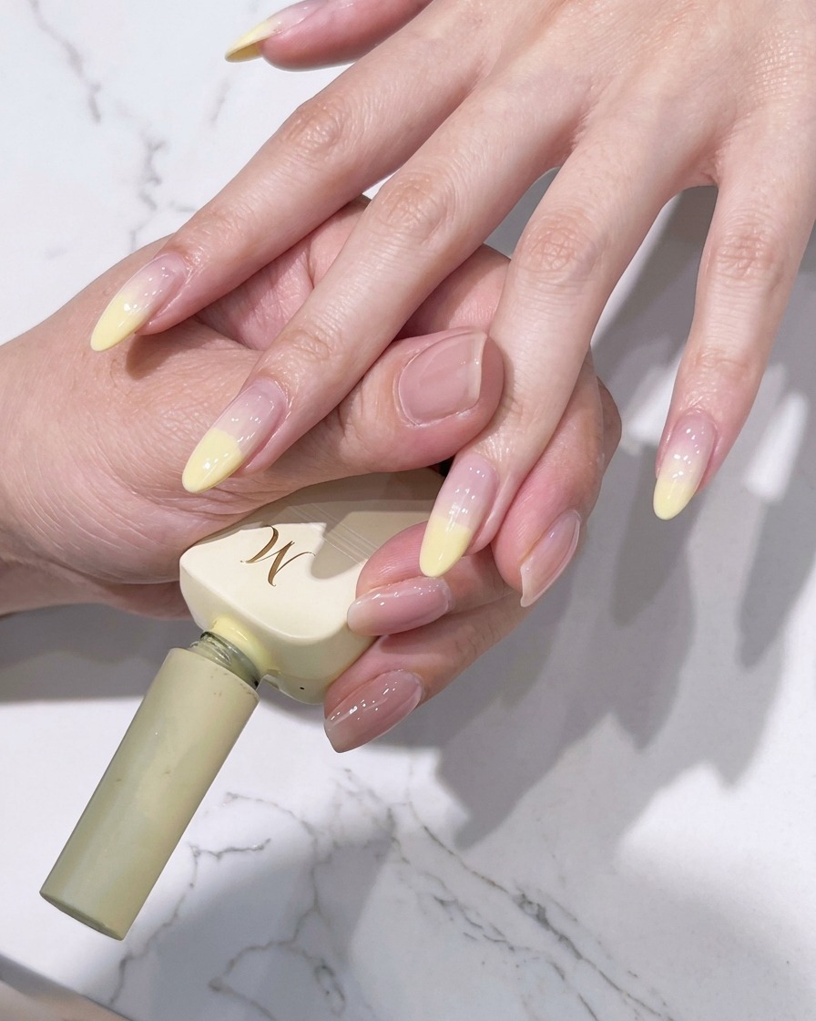 A close-up view of a brush blending the yellow tip color downward into the center of the nail.