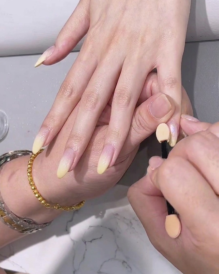 Applying a final clear top coat over the chrome-effect nails.
