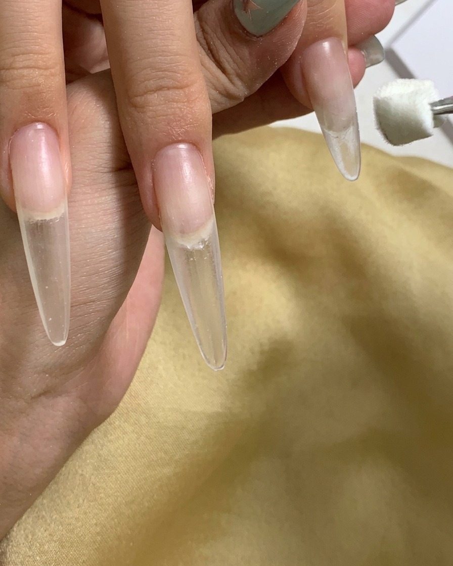 A close-up showing a sponge dabber applying gel to the cuticle area of the nail.