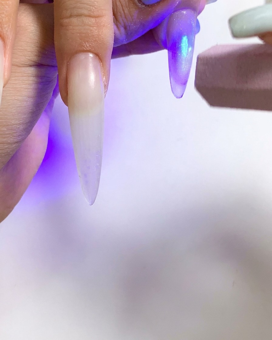A small UV flashlight being used to cure a single nail with a cat eye effect.