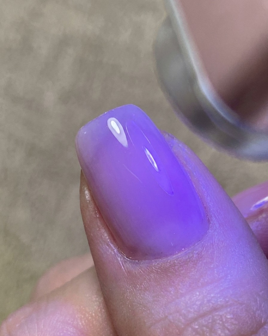 A thin layer of clear gel being applied to the nail, creating a glossy, tacky surface.