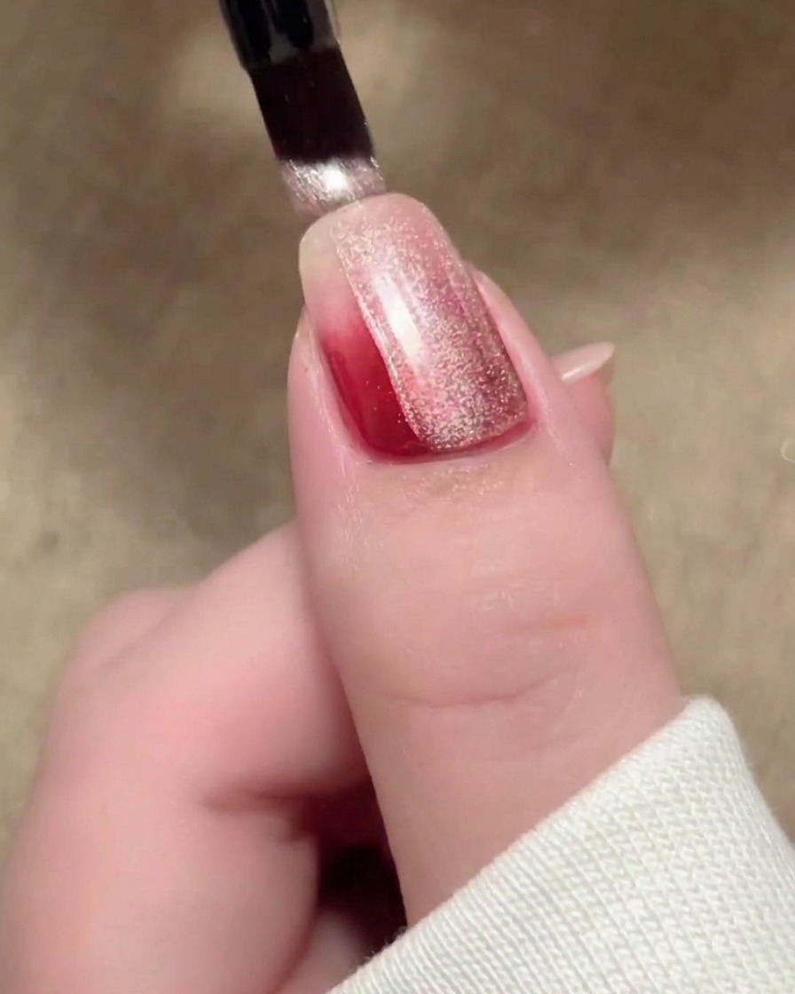 A brush stroke of beige magnetic cat-eye polish covering the surface of the nail.