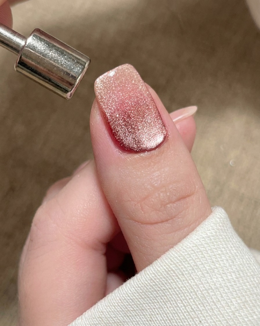 A close-up of a magnet being used to push the magnetic shimmer toward the free edge of the nail.