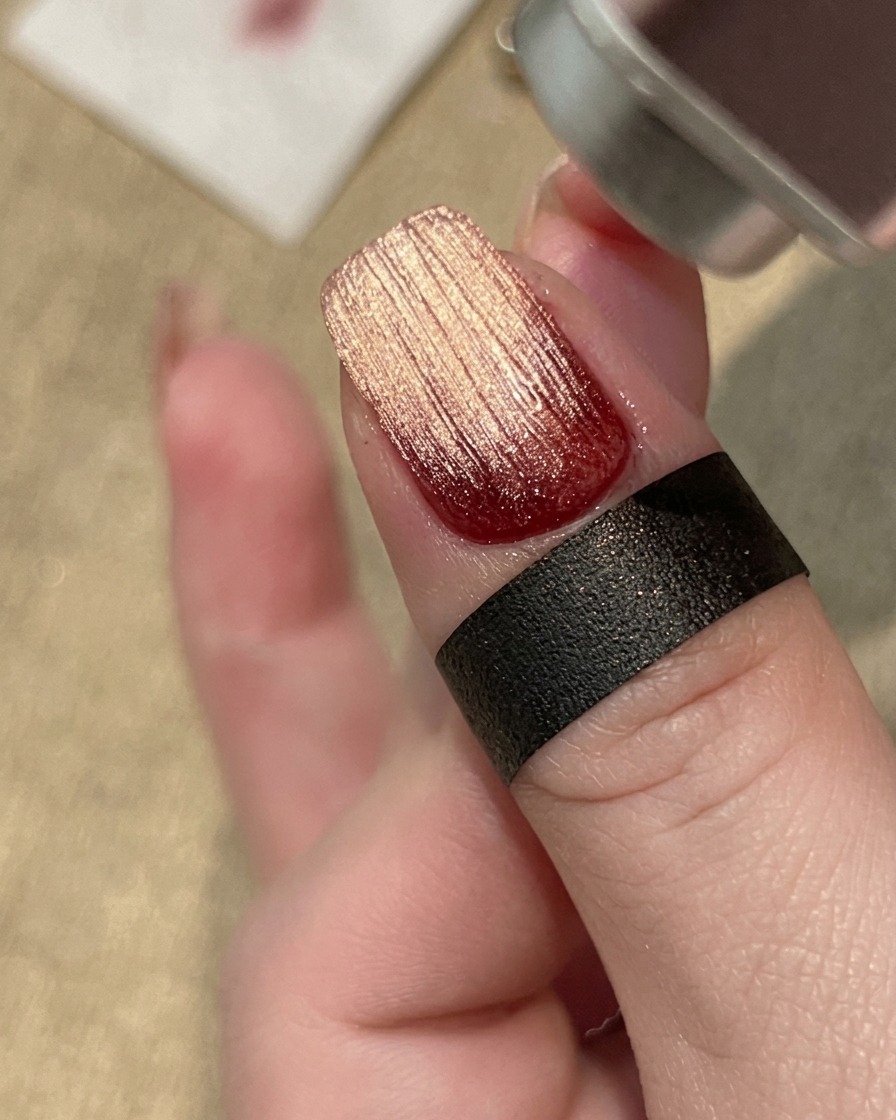 A hand curing a textured gel nail design underneath a professional UV/LED lamp.