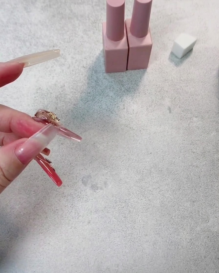A close-up of a nail receiving a second coat of dark red gel polish, showing increased color depth.