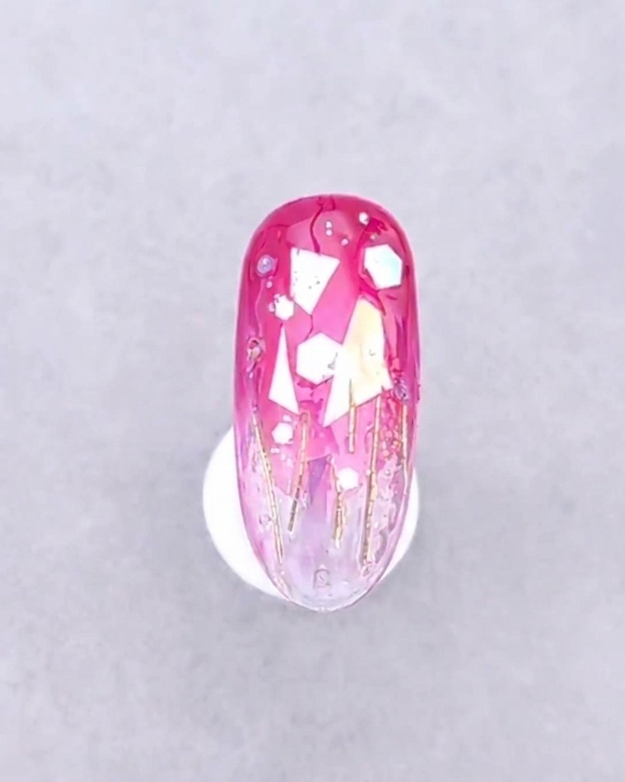 A nail with placed decorations positioned under the purple light of a UV nail lamp.