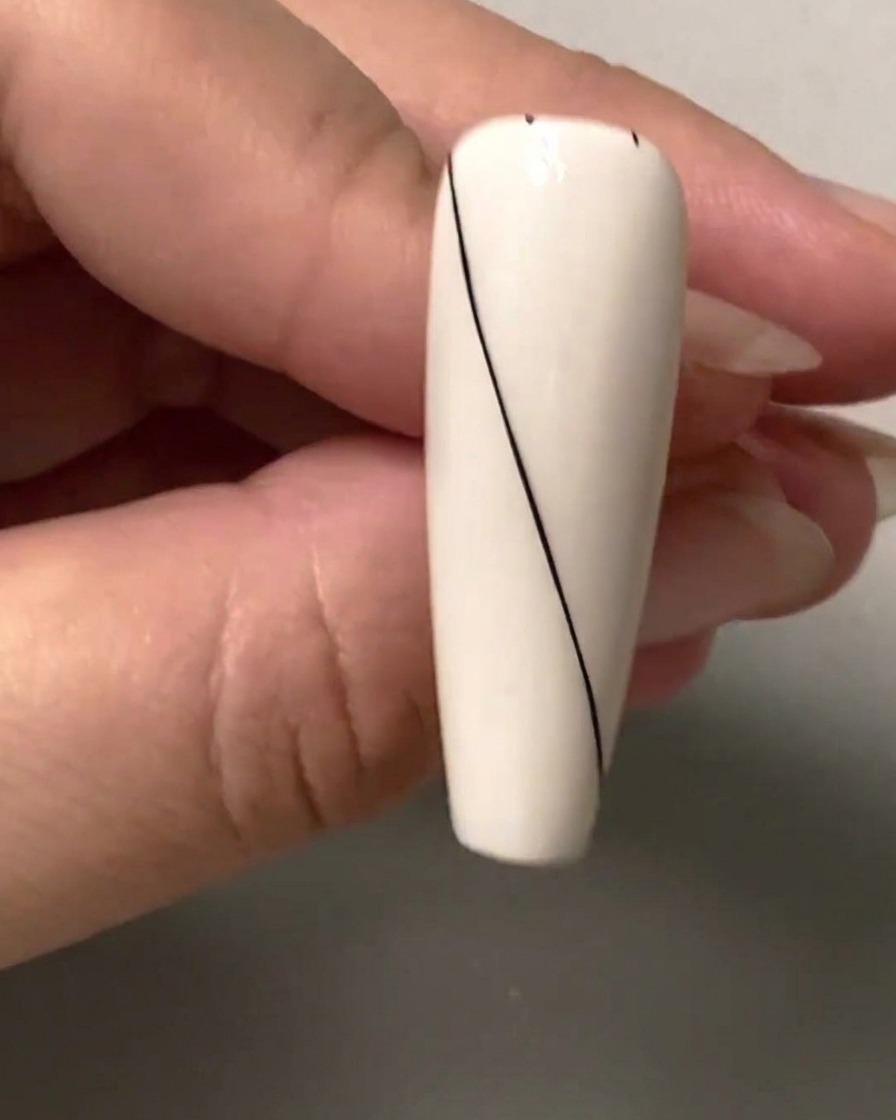 A close-up of a nail showing small black spacing dots marked along the upper right blank section.