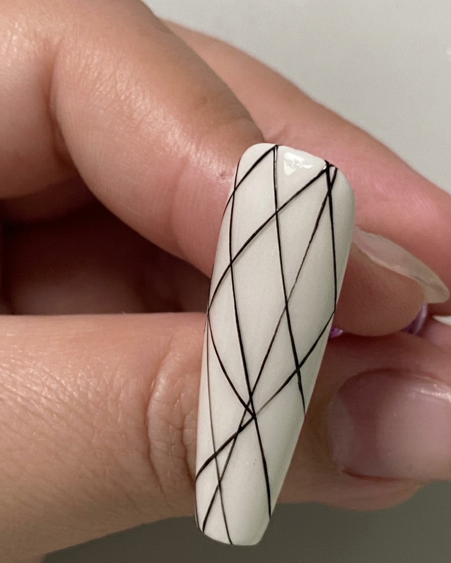 A close-up of a nail showing small black spacing dots marked along the bottom section.