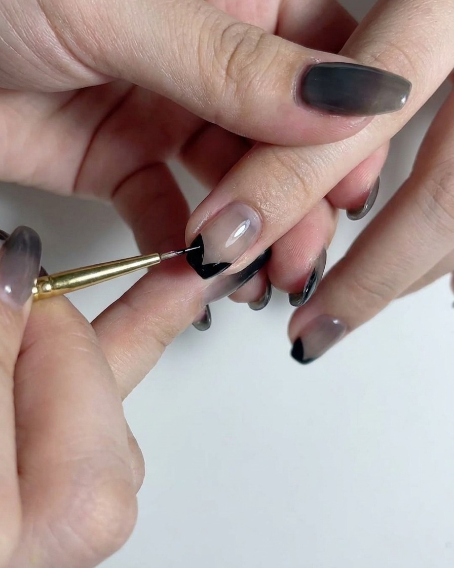 A fine liner brush drawing a straight vertical black line down the center of a smokey translucent gradient nail.