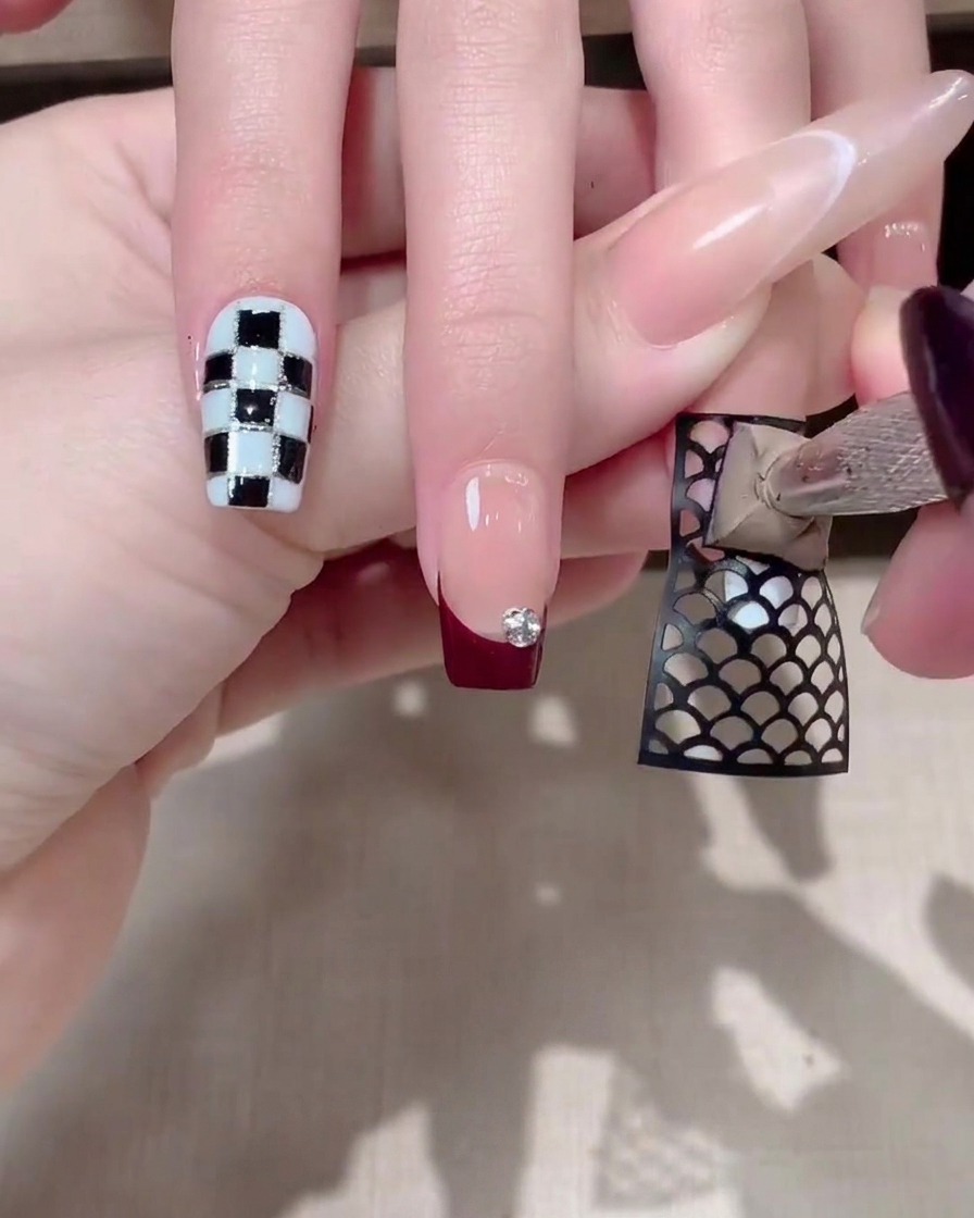 A sponge tool dabbing thick grey gel over a black mesh sticker on a fingernail.