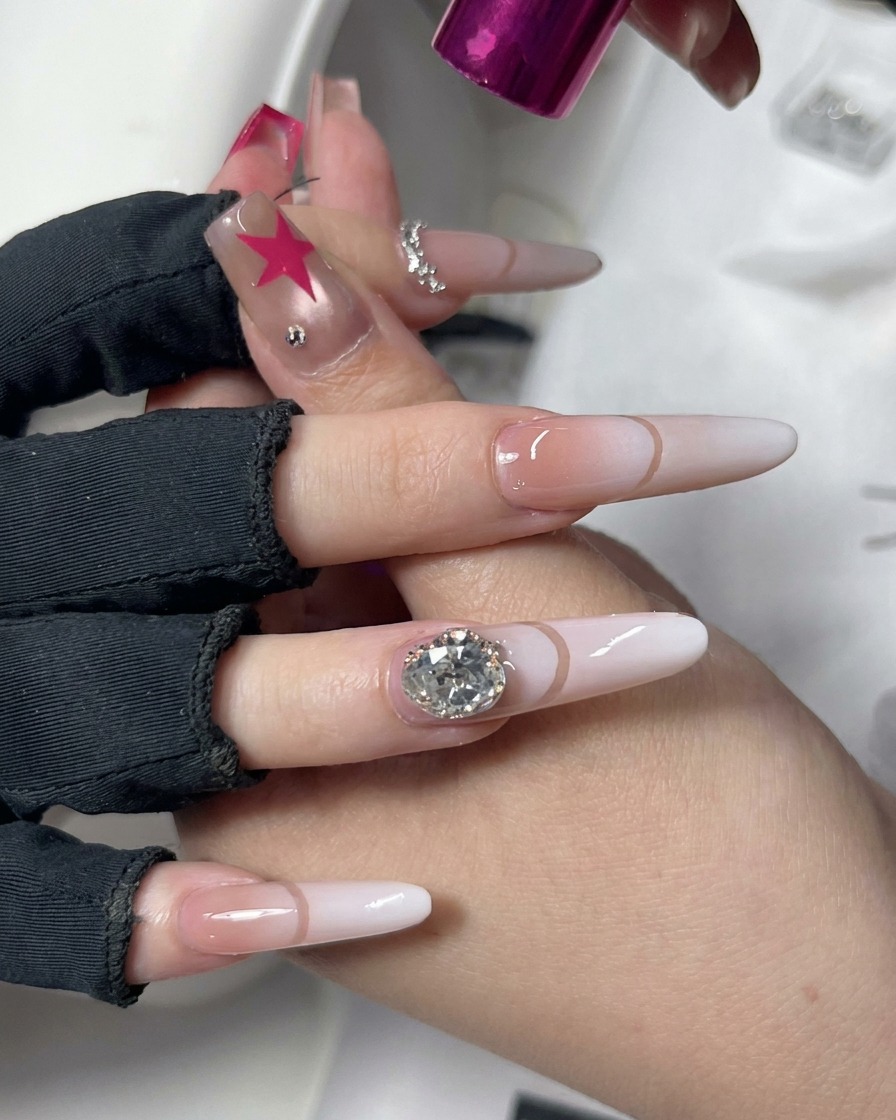 A hand positioned under a compact pink UV/LED nail curing lamp with decorative nail art.