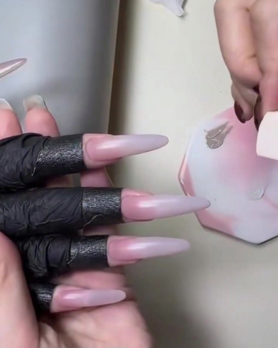 A sponge applying nude skin-toned gel next to a white palette during a gradient nail tutorial.