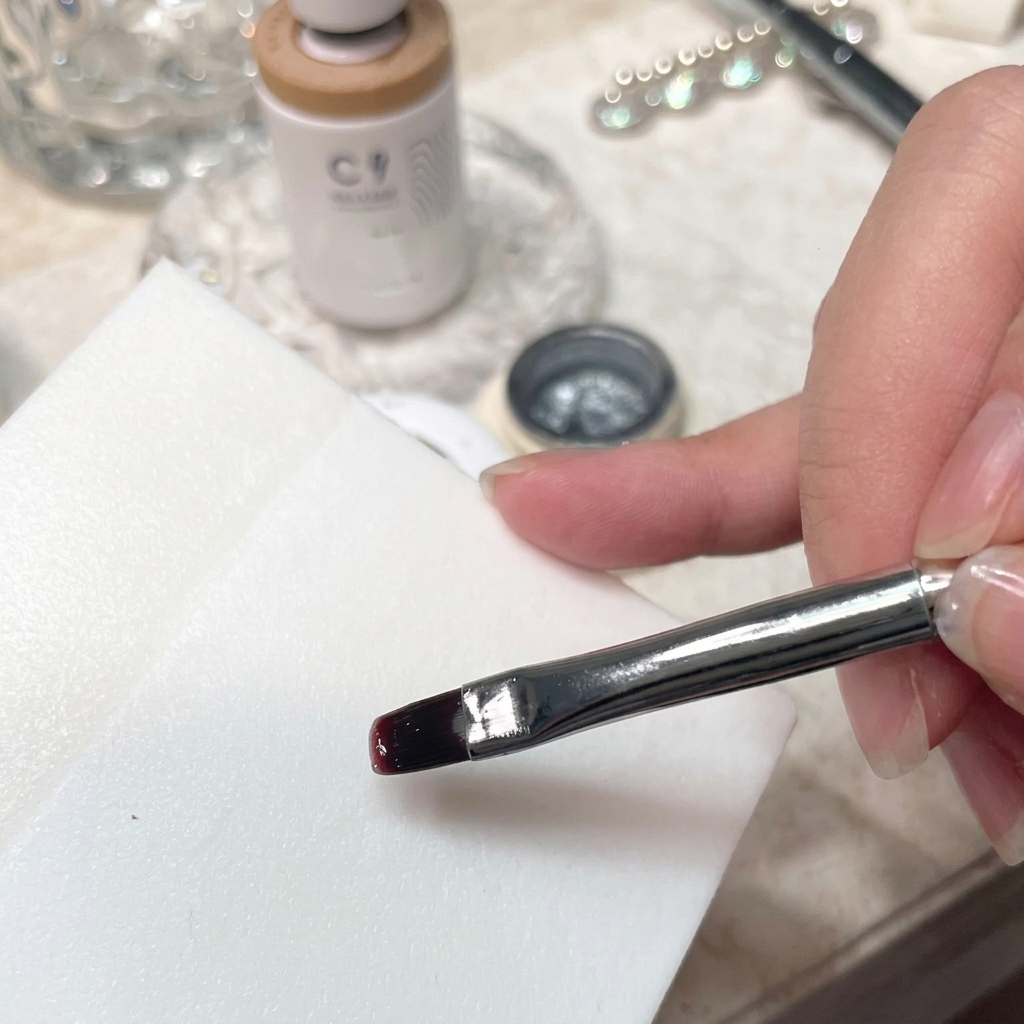 A detailed close-up of a brush mixing gel polish on a smooth white palette surface.